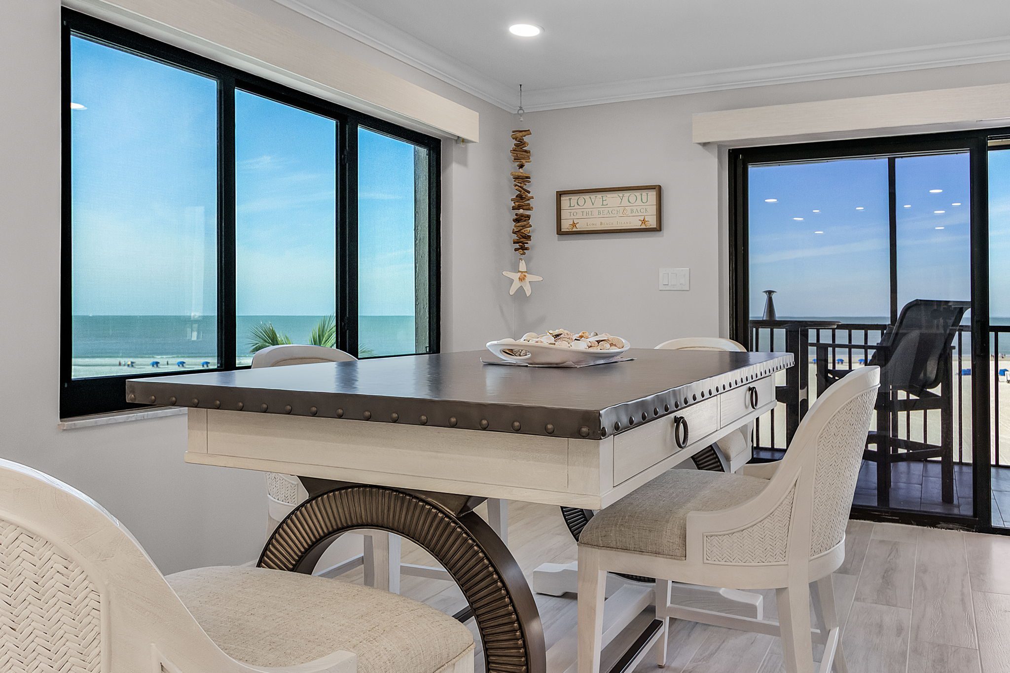 Luxury beachfront condo dining area with panoramic ocean views and access to coastal porch—Southwest Florida coastal living at its finest