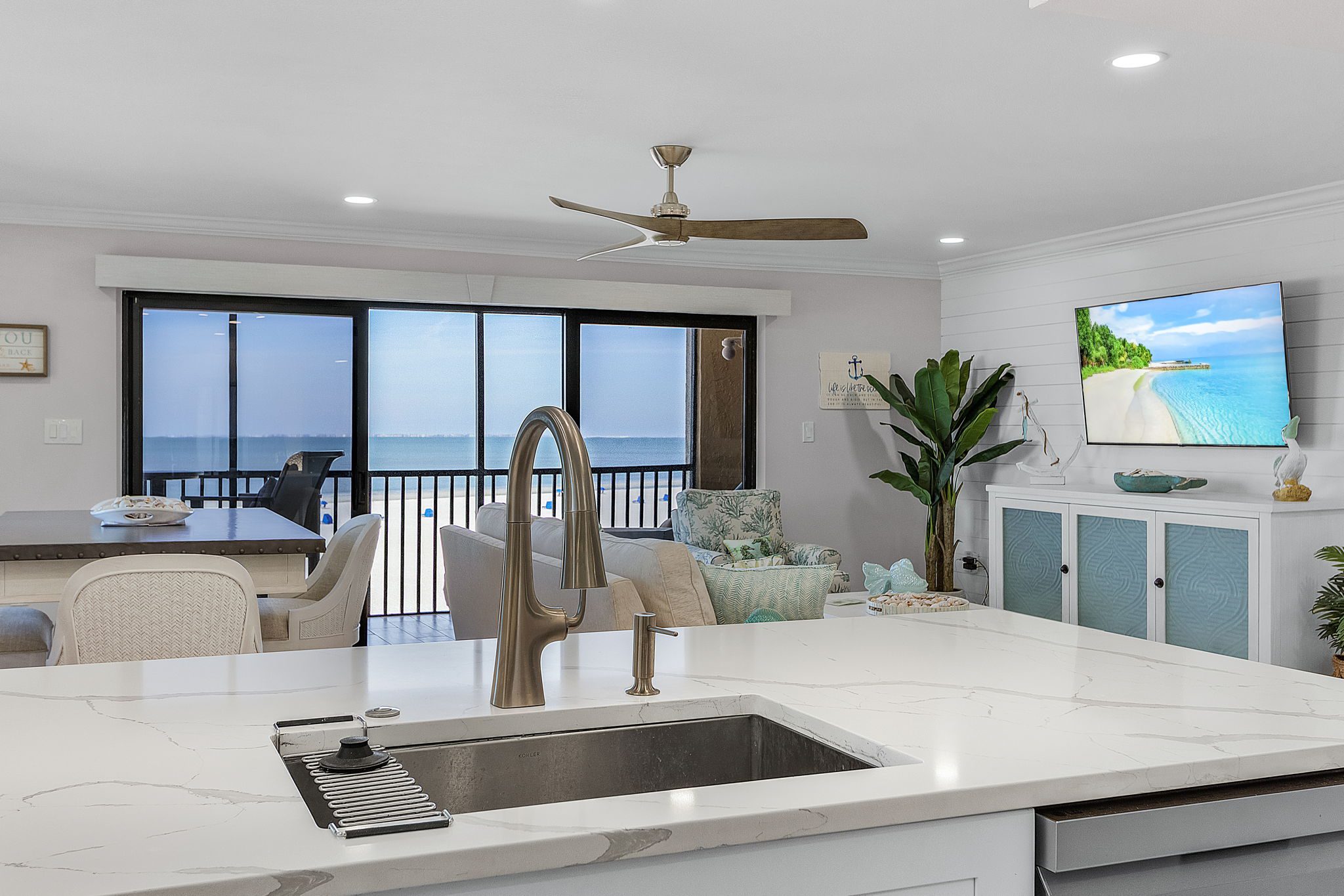 Open-concept luxury condo kitchen flowing into living space and beachfront porch with ocean views in Fort Myers Beach