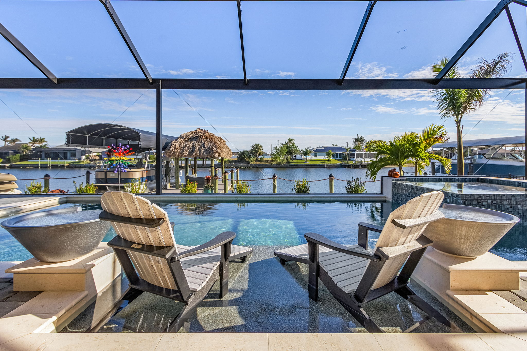 Southwest Florida luxury home pool with screened lanai, Adirondack chairs, and serene lake views—ideal for waterfront living