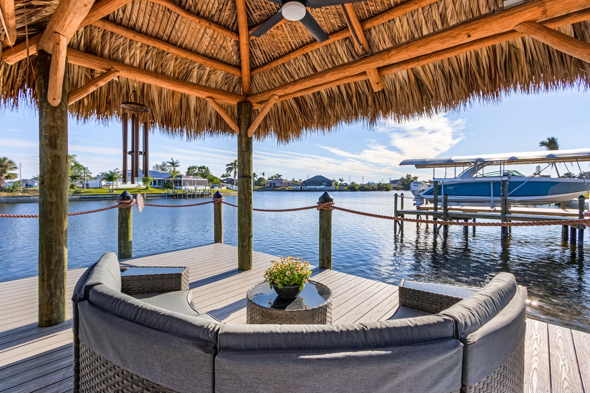 Cape Coral canal view from tiki hut seating area with waterfront homes beyond—offering a taste of Southwest Florida’s relaxed waterfront lifestyle