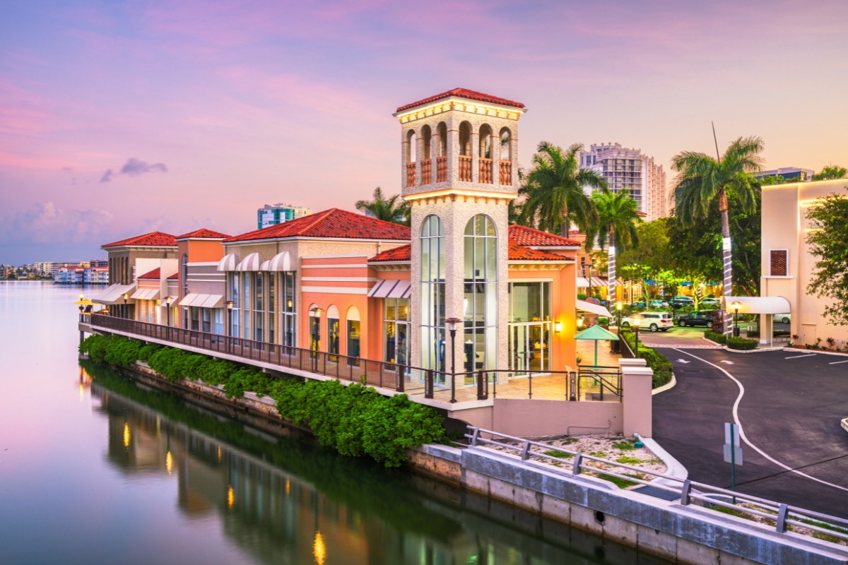 Naples sunset reflecting on glassy water with luxury waterfront shops—highlighting Southwest Florida’s upscale shopping, dining, and real estate