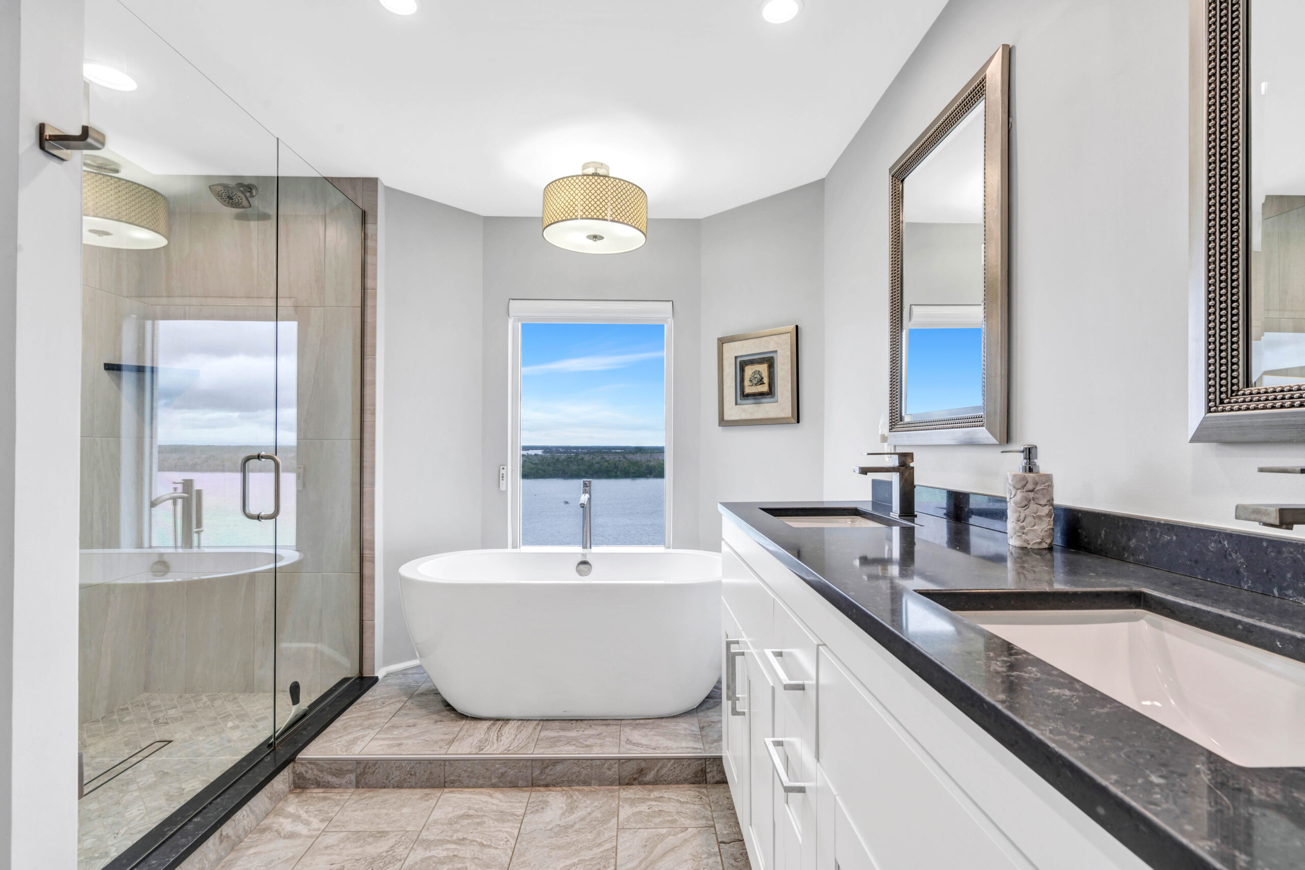 Bright, modern Southwest Florida luxury bathroom featuring a soaking tub, glass-enclosed shower, and elegant coastal design